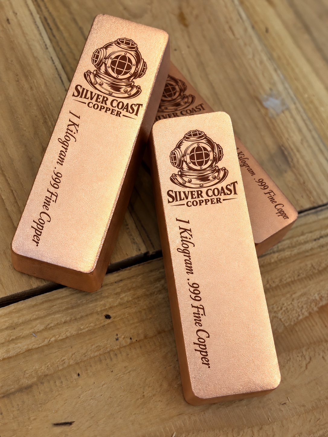 Angled stacked view of 1 kilogram .999 fine copper bars with diver's helmet logo in satin finish