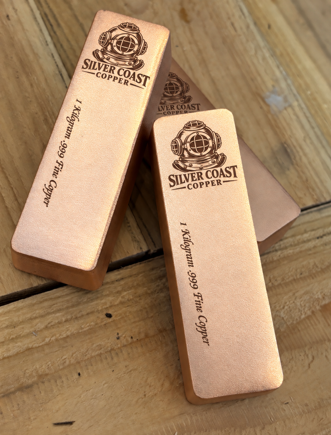 Stacked 1 kilogram satin copper bars showing the Silver Coast Copper diver's helmet engraving