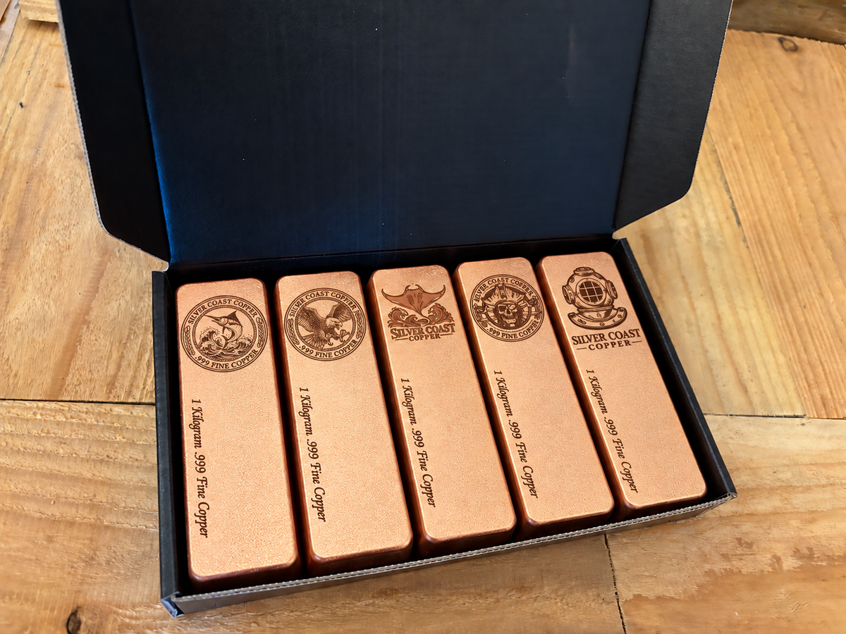 Mixed Silver Coast Logos five-pack: five 1 kilogram .999 fine copper bars in satin finish, displayed in an open black presentation box